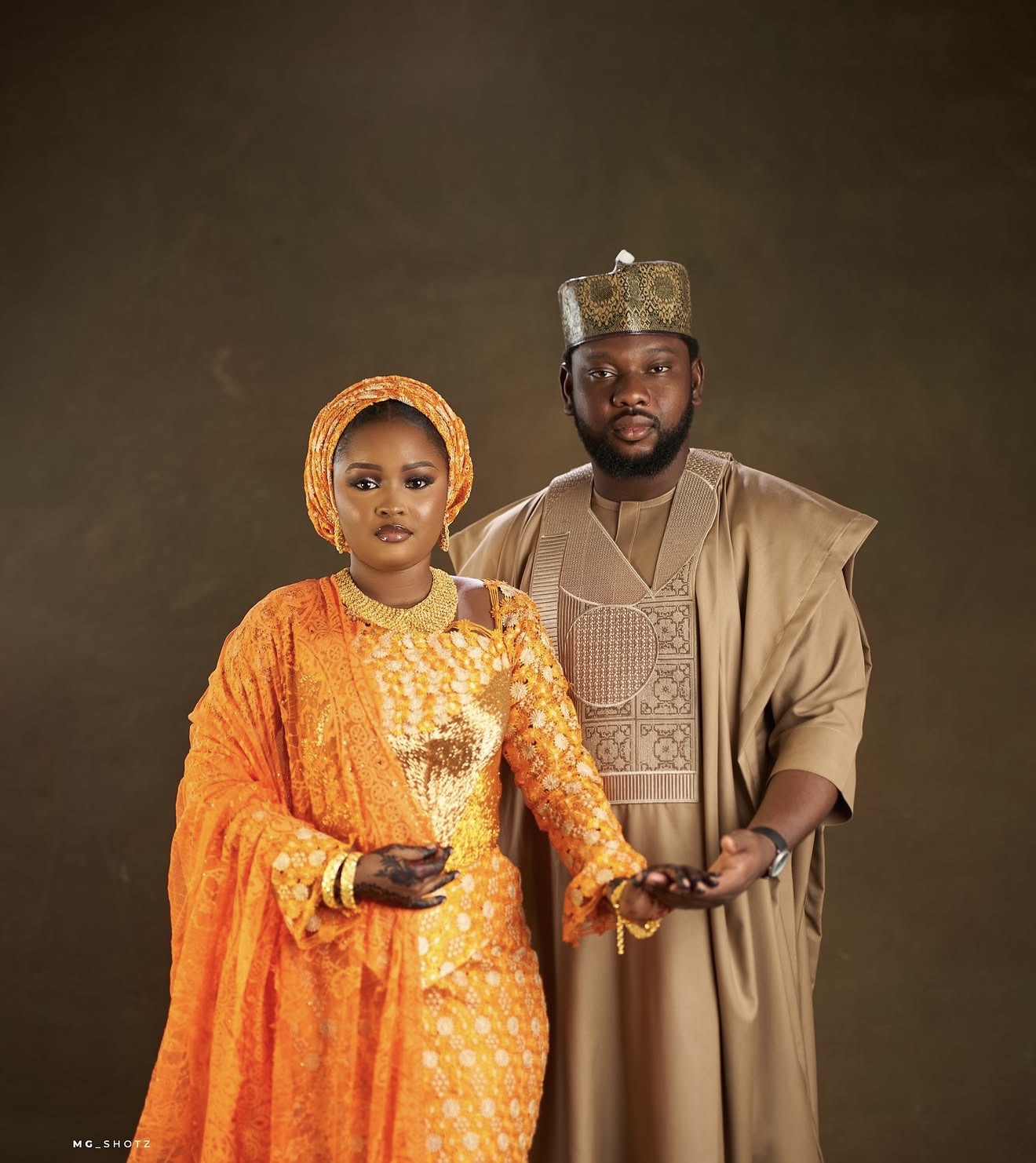 Couple holding hands in orange and gold traditional attire