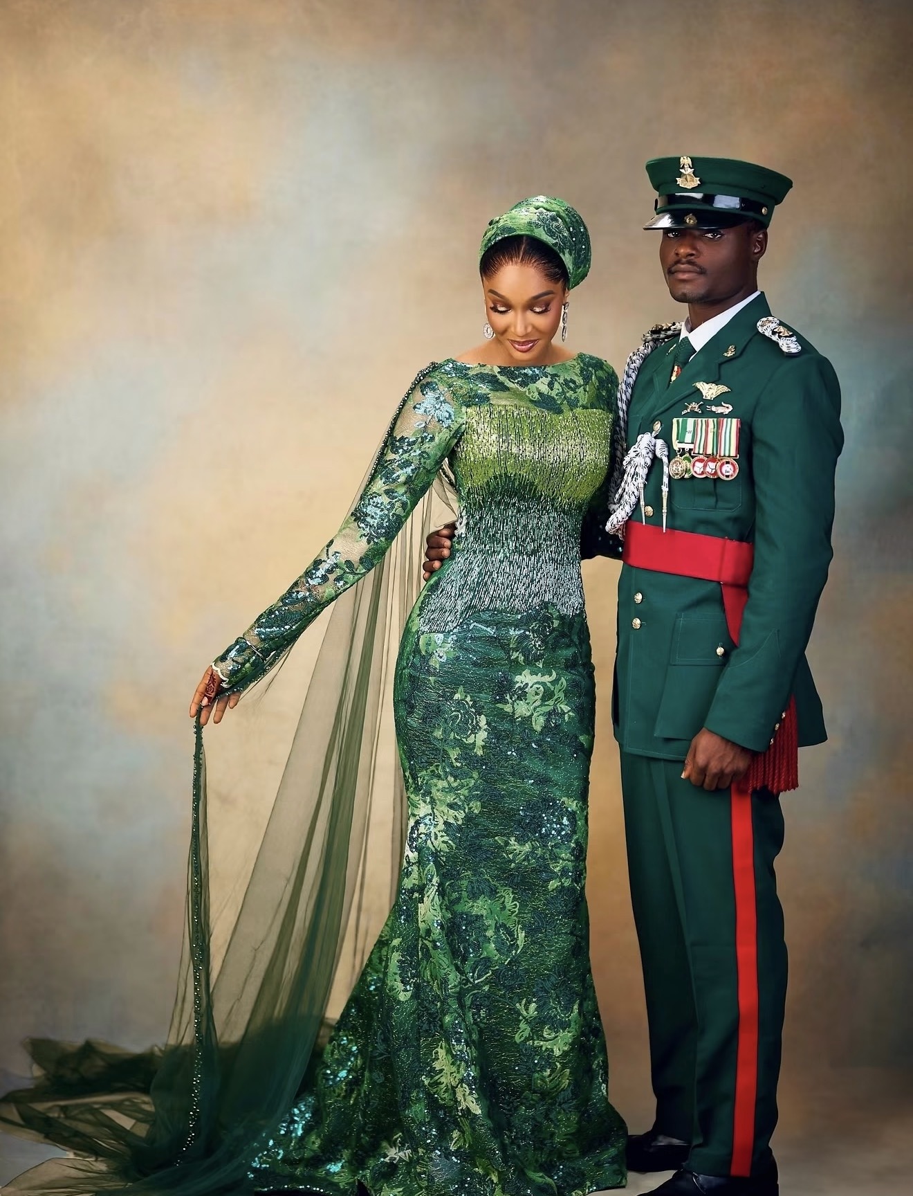 Couple in an emerald gown and formal military dress uniform against a painted backdrop